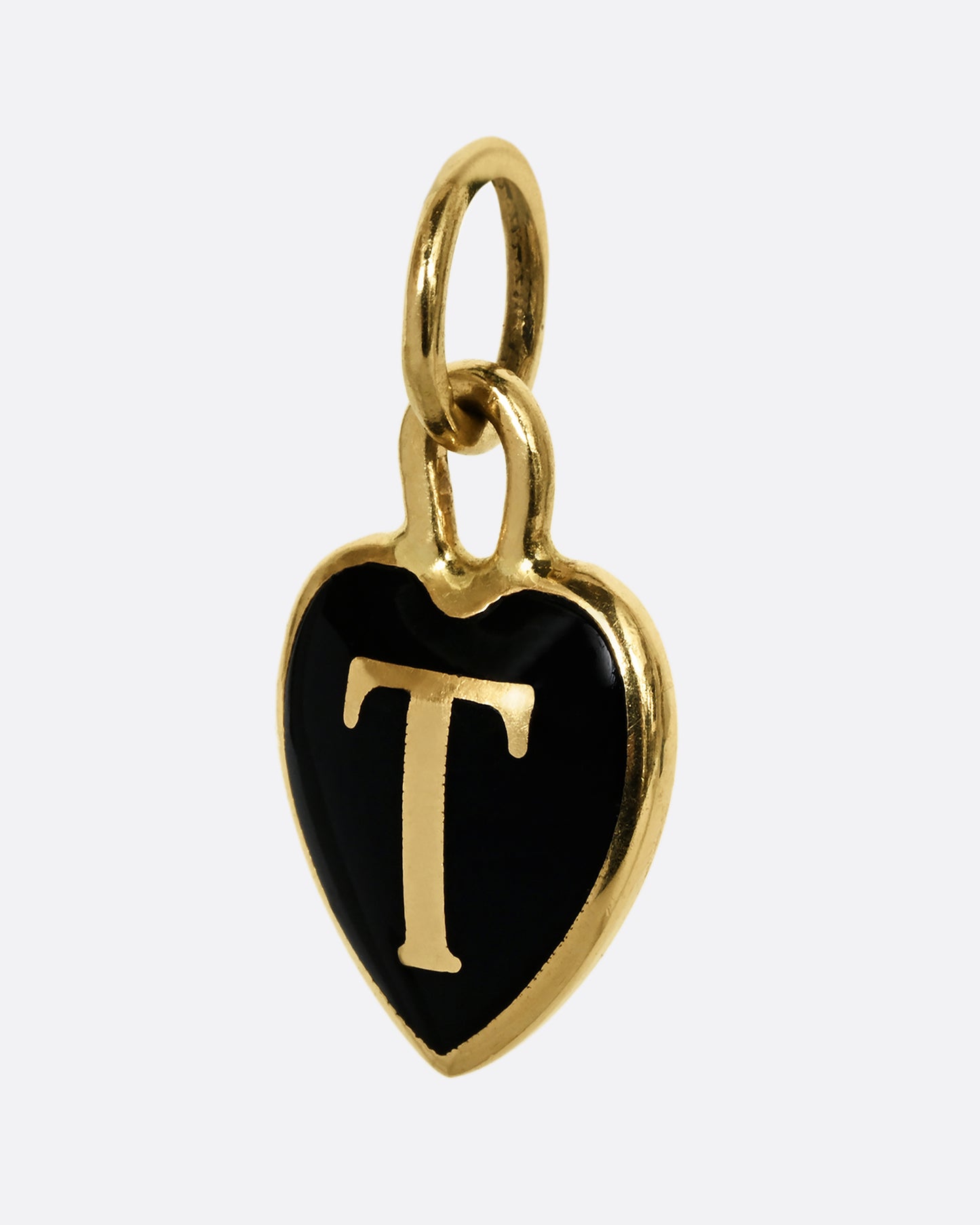 A yellow gold letter "T" heart shaped charm with black enamel. Shown from the side.