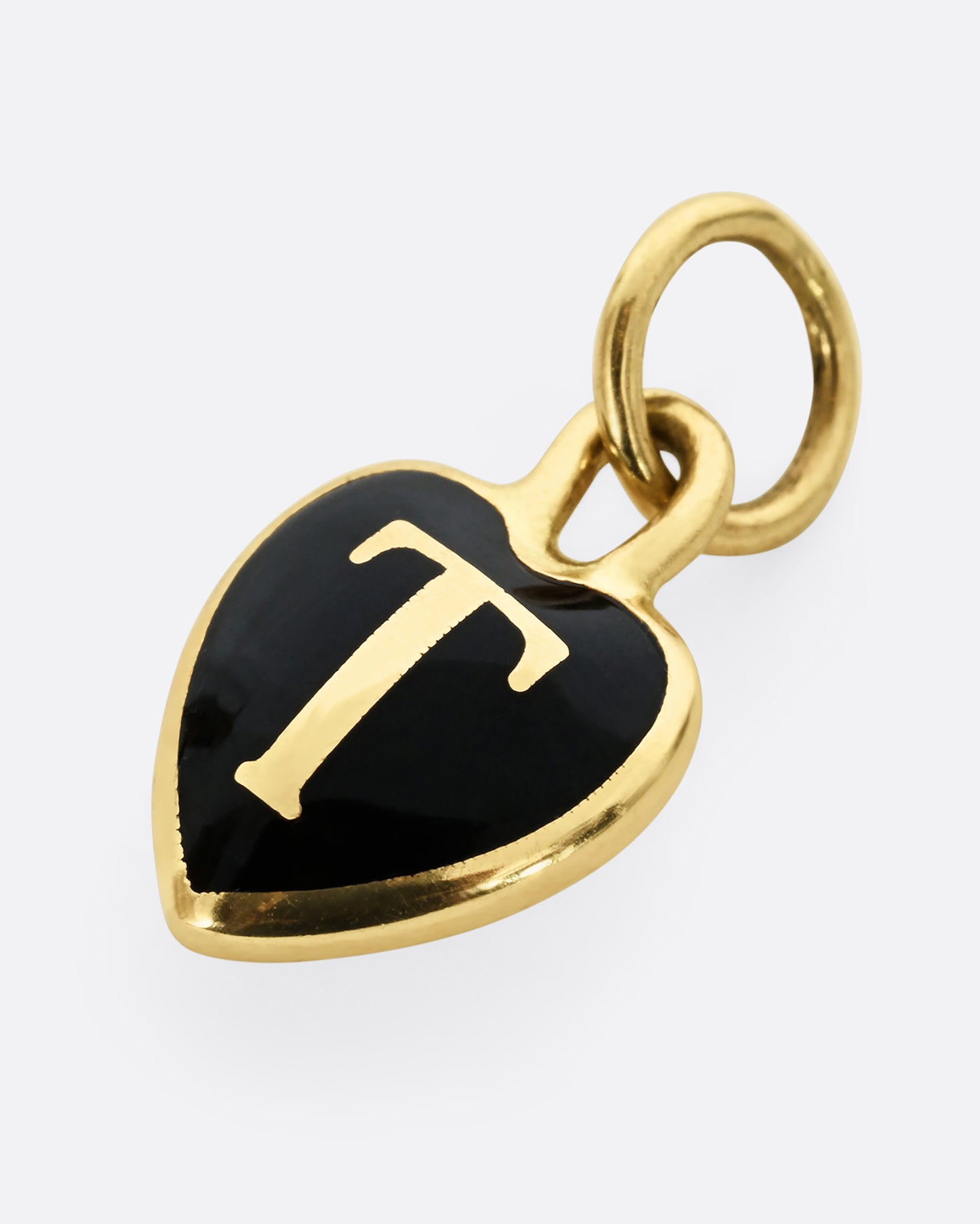 A yellow gold letter "T" heart shaped charm with black enamel. Shown laying flat.