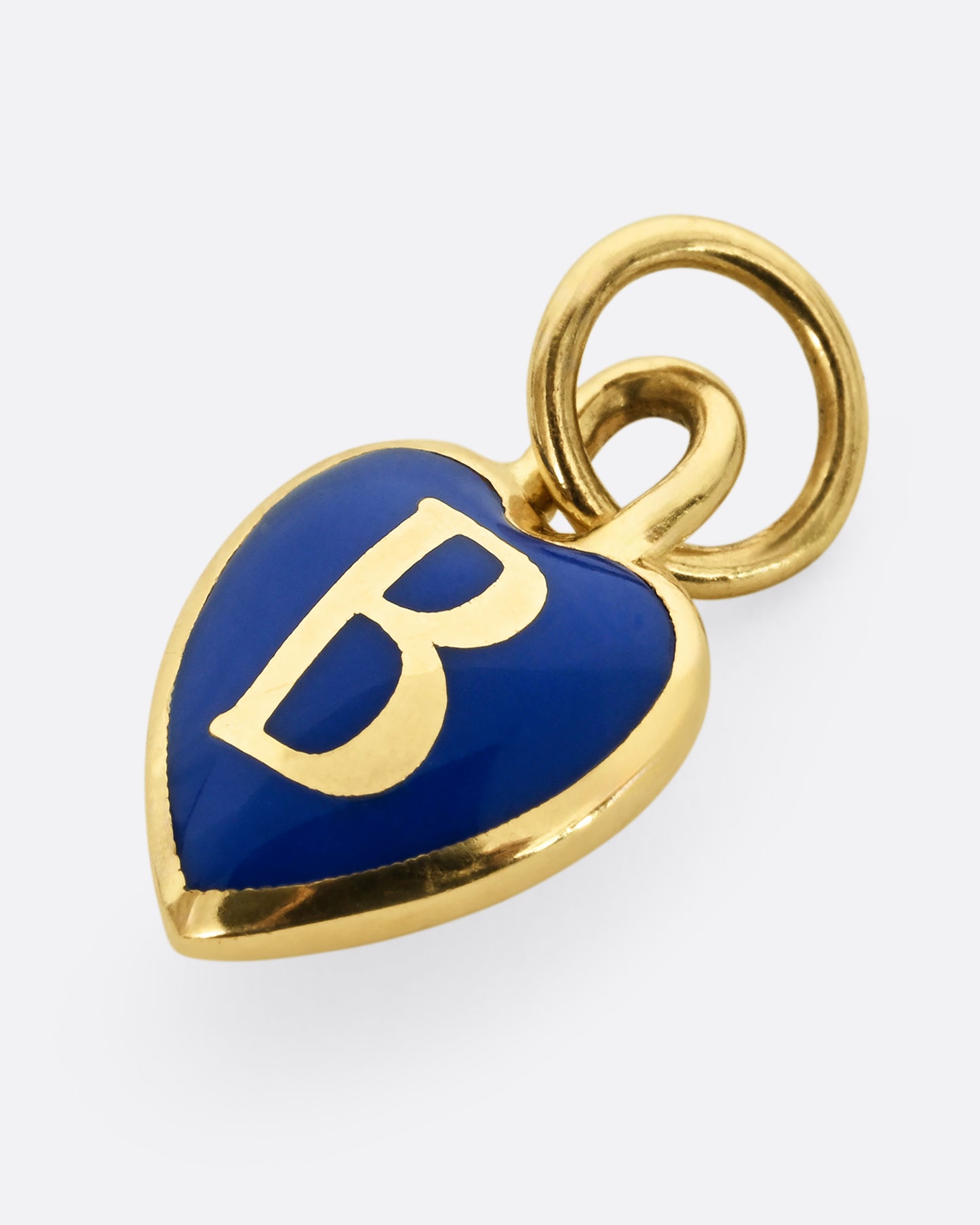 A yellow gold letter "B" heart shaped charm with blue enamel. Shown from the front, laying flat.