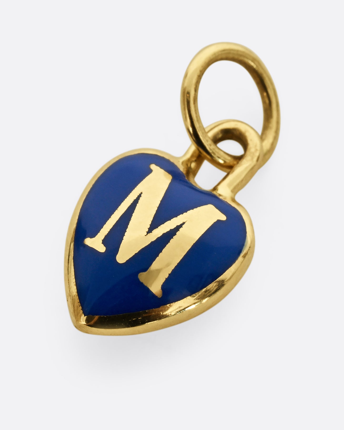 A yellow gold letter "M" heart shaped charm with blue enamel. Shown from the front, laying flat.