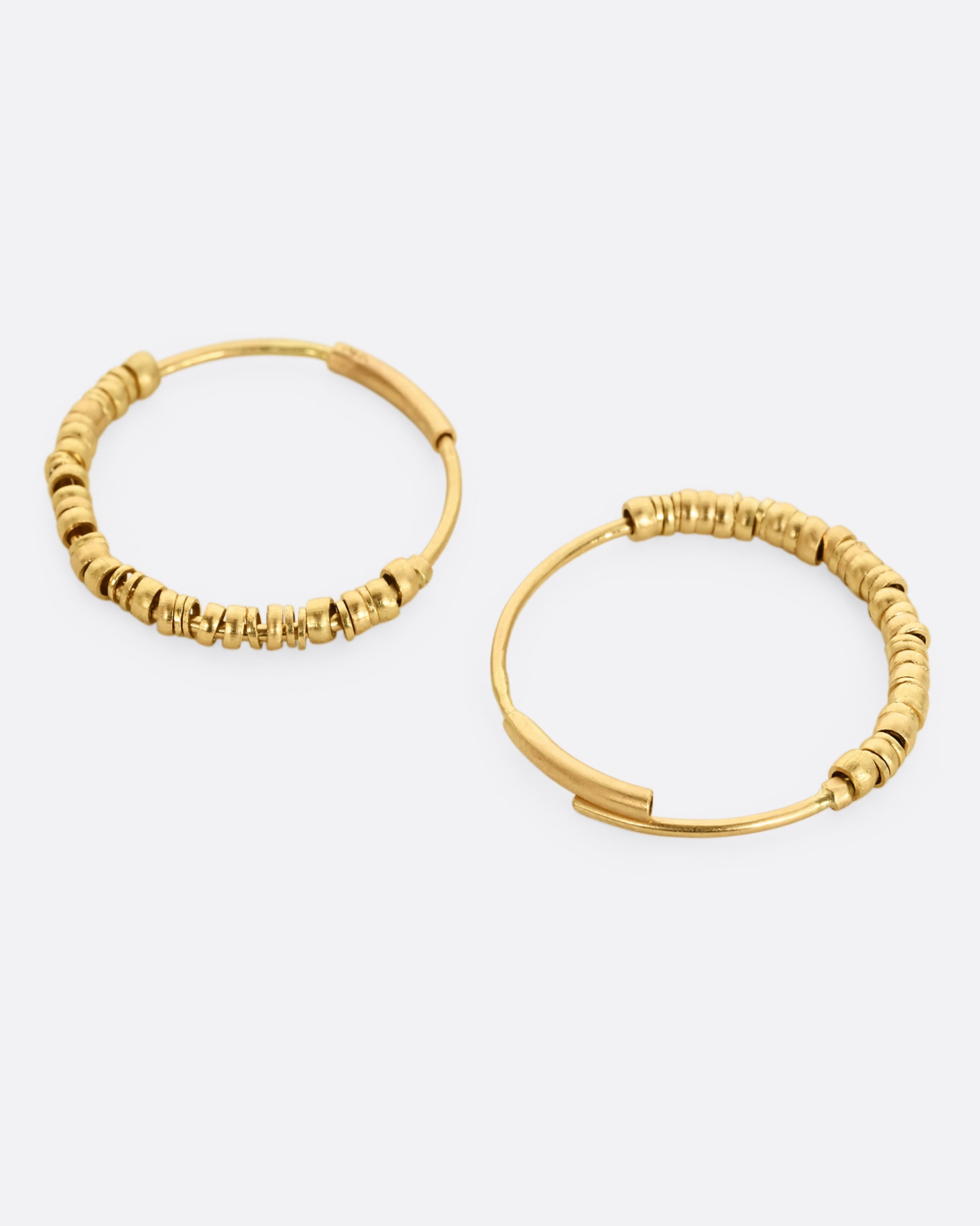 Yellow gold hoop earrings with beads and tube closure. Shown open, laying flat.