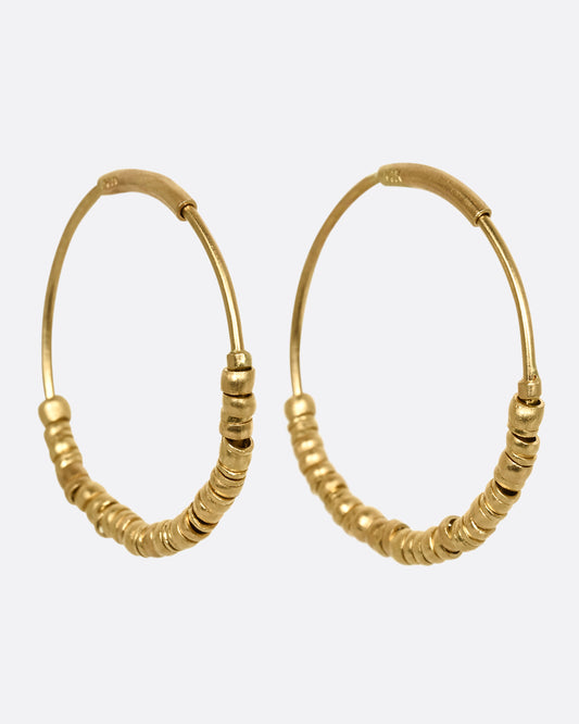 Yellow gold hoop earrings with beads and tube closure. Shown from the side.