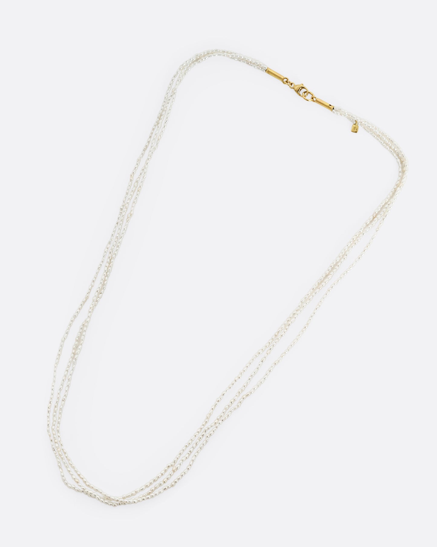 A three strand pearl necklace, shown laying flat.