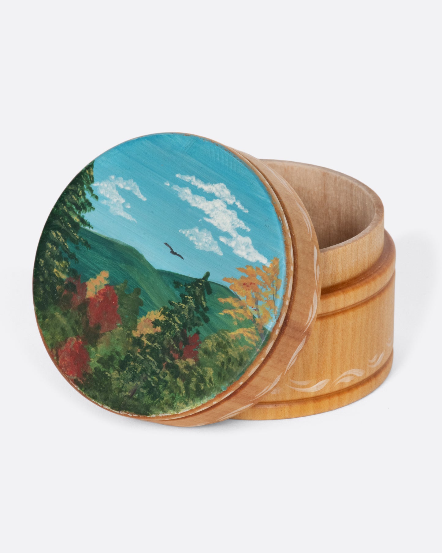 A vintage round wooden box with a beautiful landscape painting on the lid.