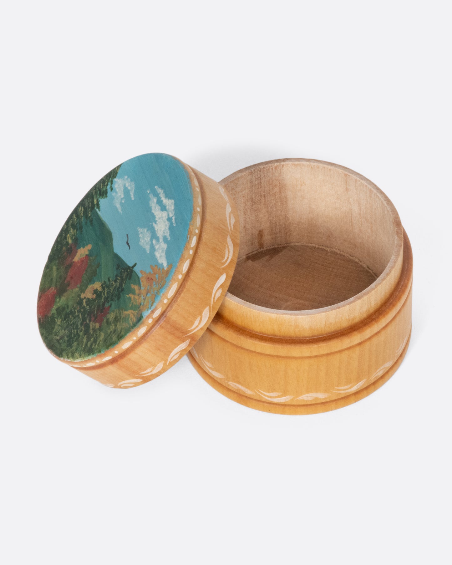 A vintage round wooden box with a beautiful landscape painting on the lid.