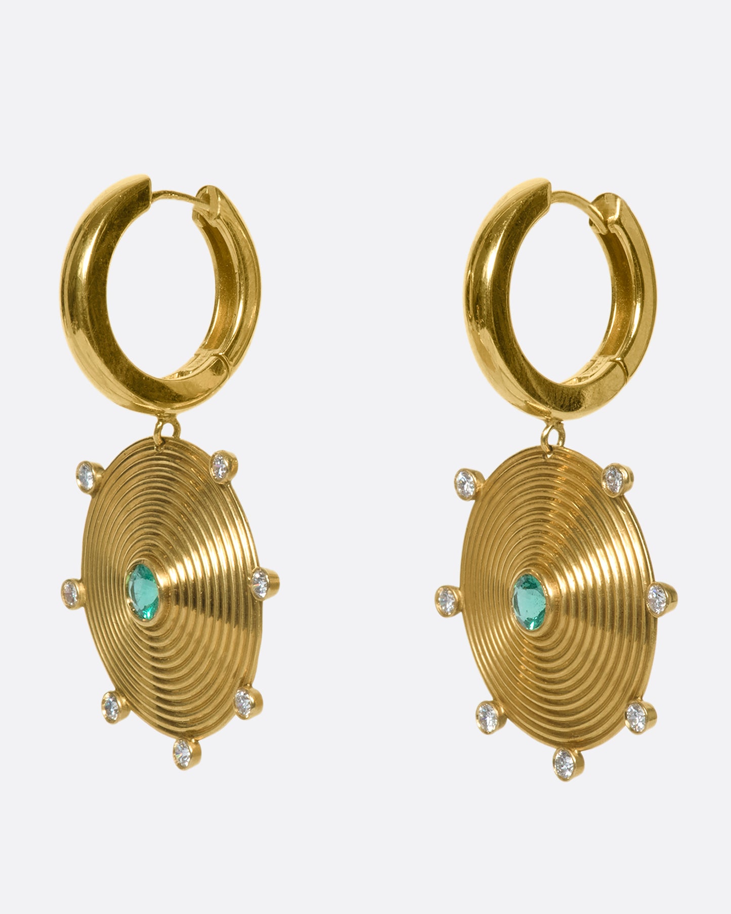 A pair of 14k gold hoops with gold disc drops, dotted with diamonds and emeralds. The discs' ribbed pattern constantly catches the light, giving the illusion of two glowing suns.