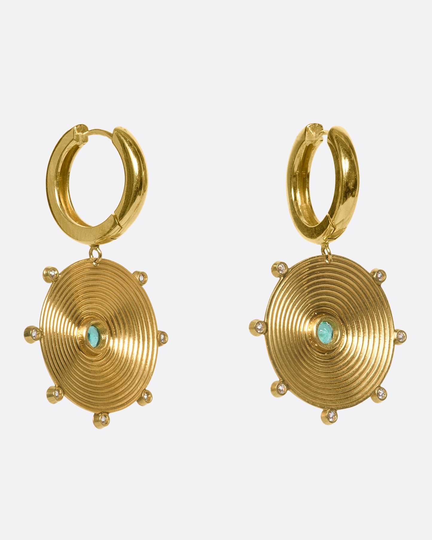 A pair of 14k gold hoops with gold disc drops, dotted with diamonds and emeralds. The discs' ribbed pattern constantly catches the light, giving the illusion of two glowing suns.