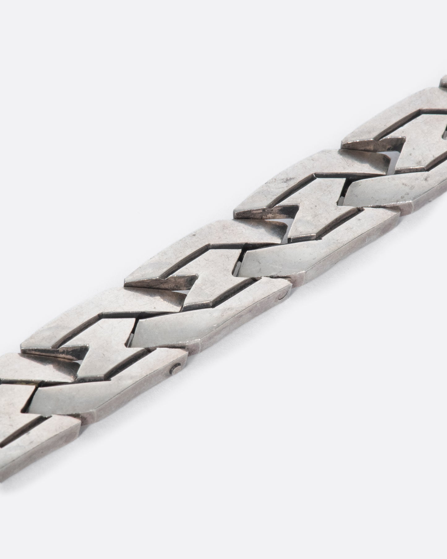 A vintage sterling silver flat chain bracelet with a woven-link design. The large, flat links reflect light making this piece especially eye-catching.