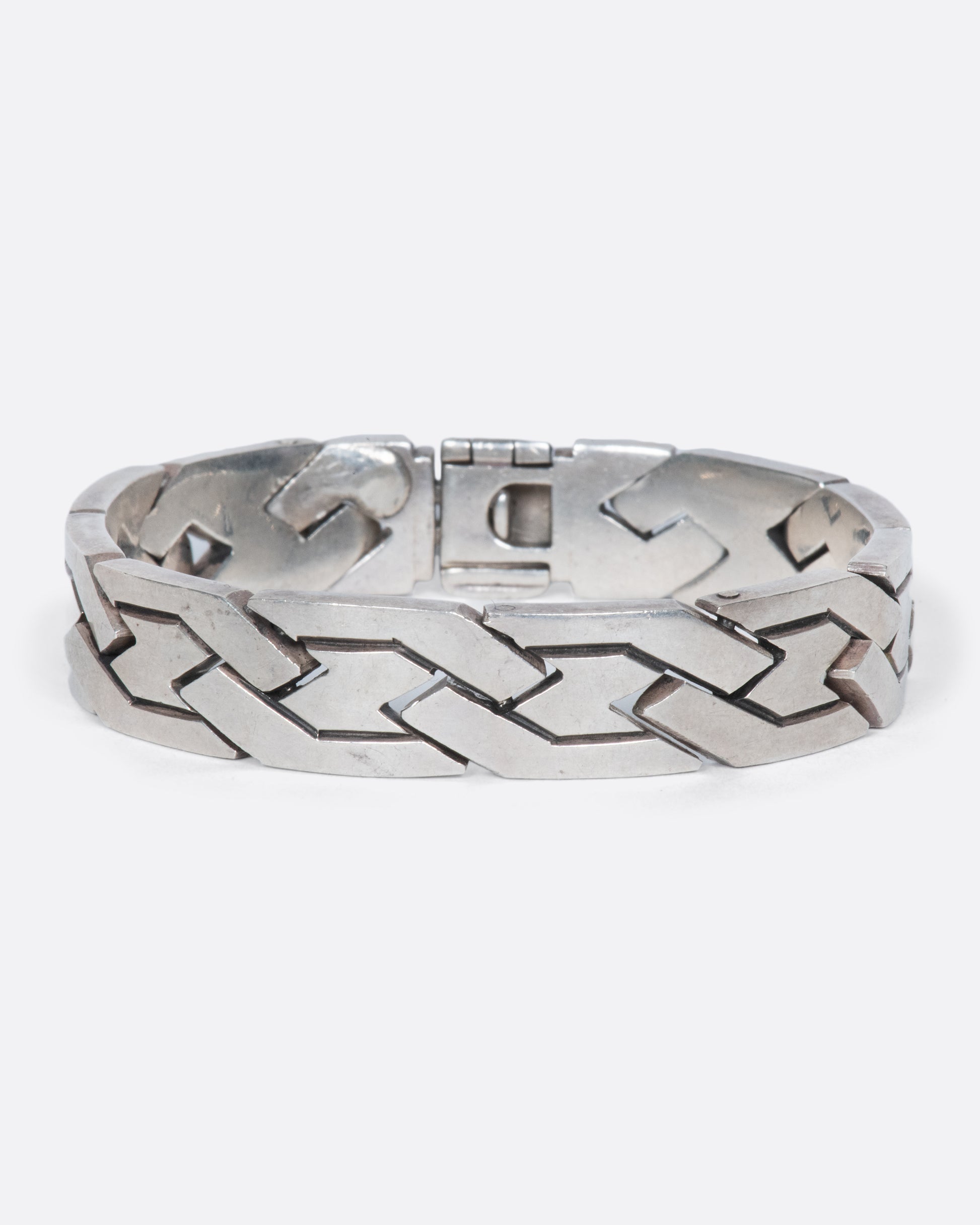 A vintage sterling silver flat chain bracelet with a woven-link design. The large, flat links reflect light making this piece especially eye-catching.