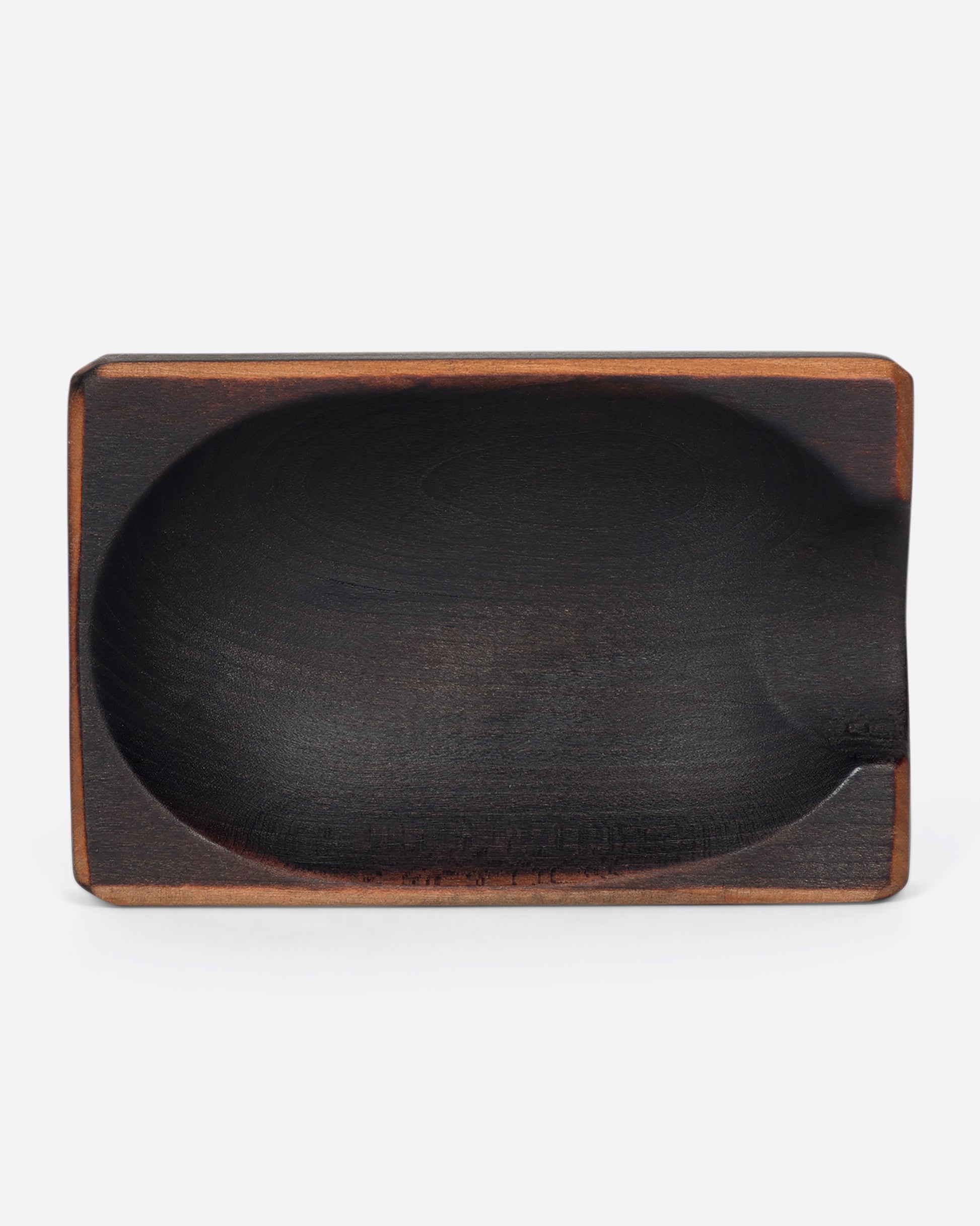 A black cherry wood spoon rest with exposed, natural wood edges.