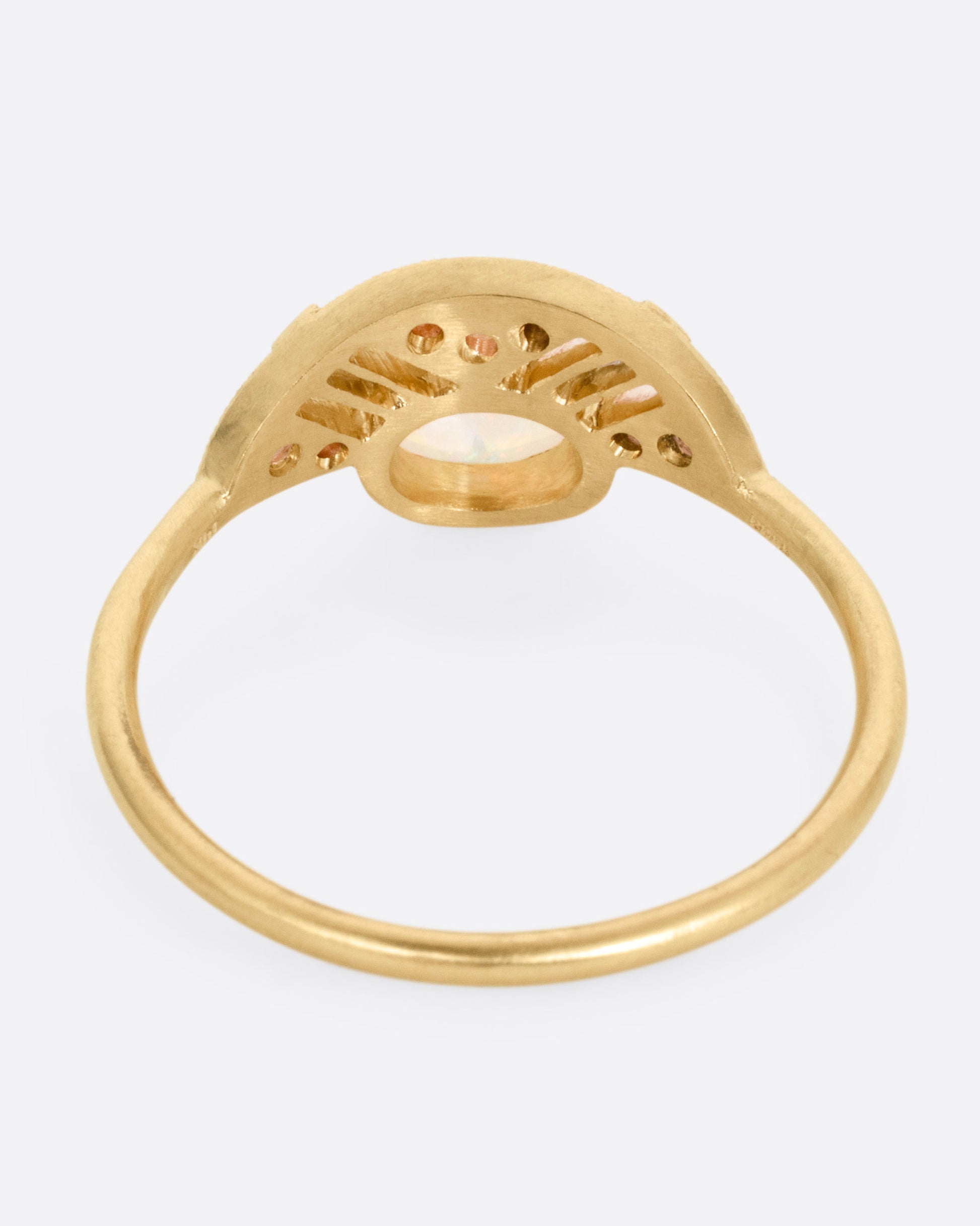A yellow gold ring with a prong set opal and a diamond studded halo, shown from the back.