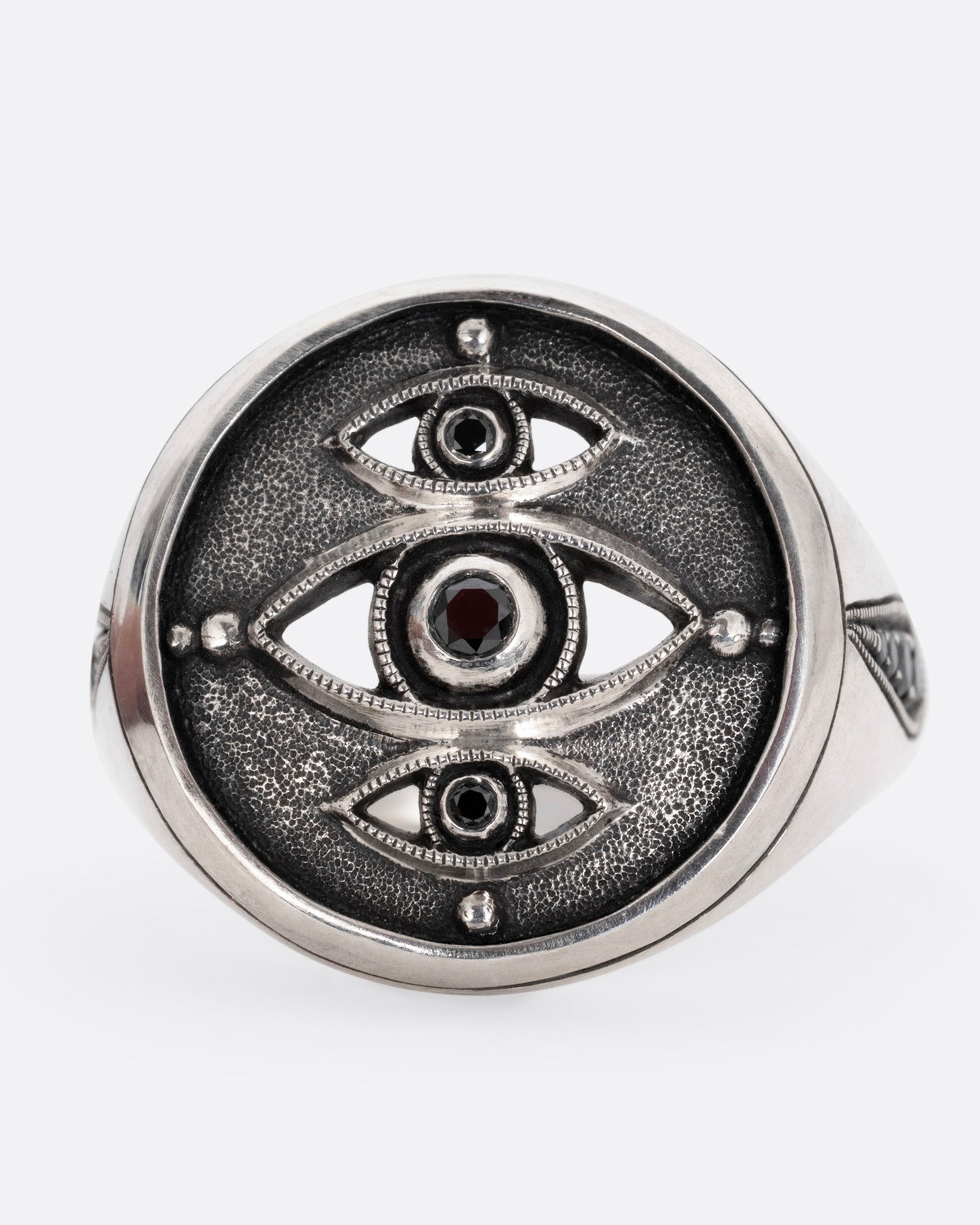A silver ring with three eyes with black diamond centers, shown from the front.