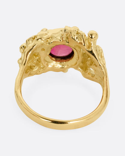 A yellow gold ring with a bed of diamond tipped anemones, and a red rubellite, shown from the back.