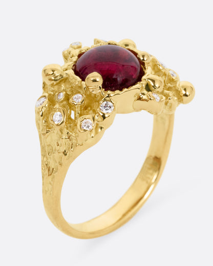 A yellow gold ring with a bed of diamond tipped anemones, and a red rubellite, shown standing up from the side.