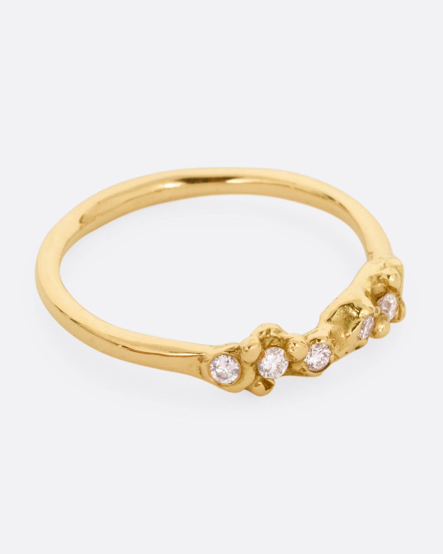 A yellow gold ring with a queue of diamonds set into a textural front. Shown from the side.