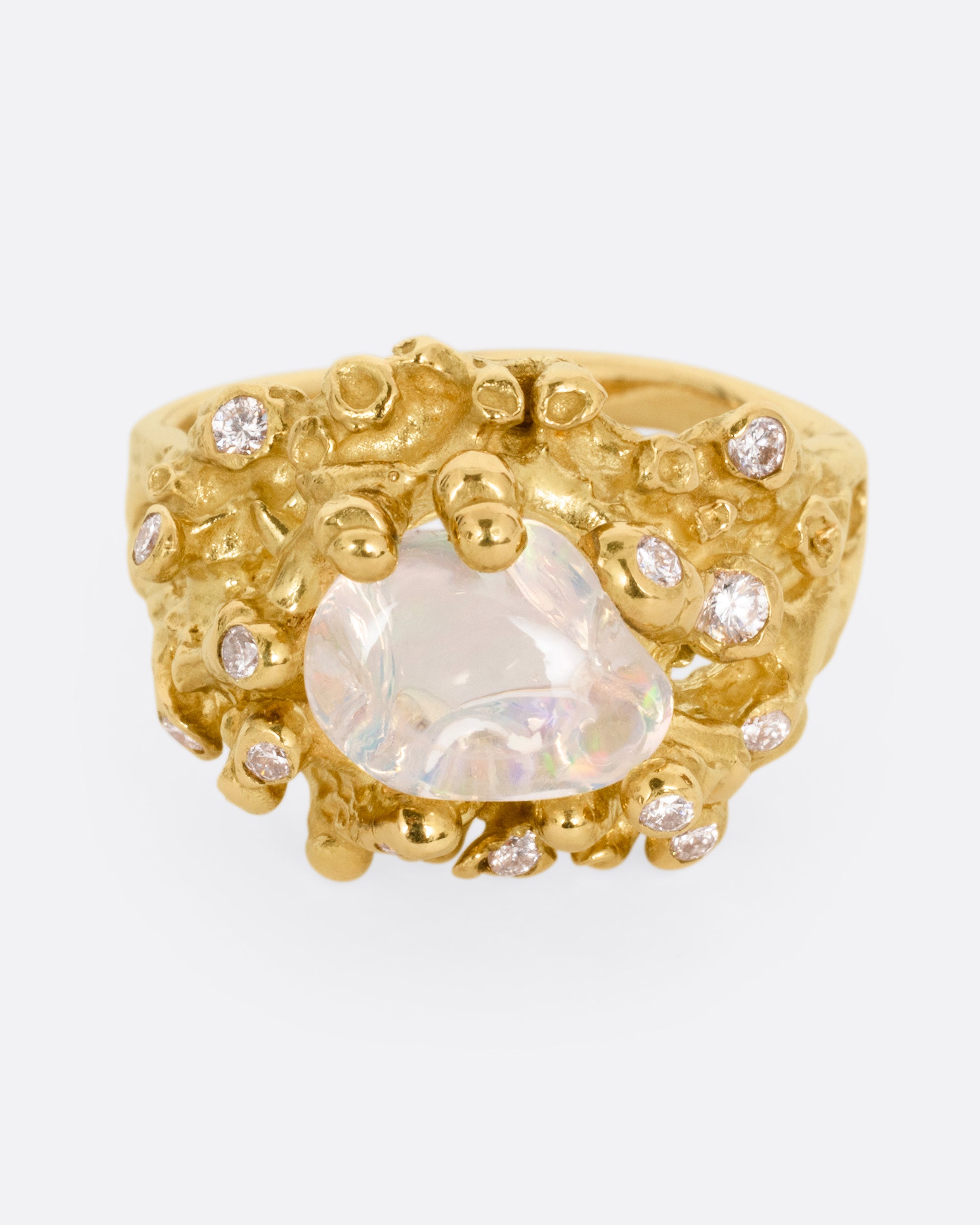 A yellow gold ring with a dimensional nest-like setting studded with diamonds and an opal, shown from the front.