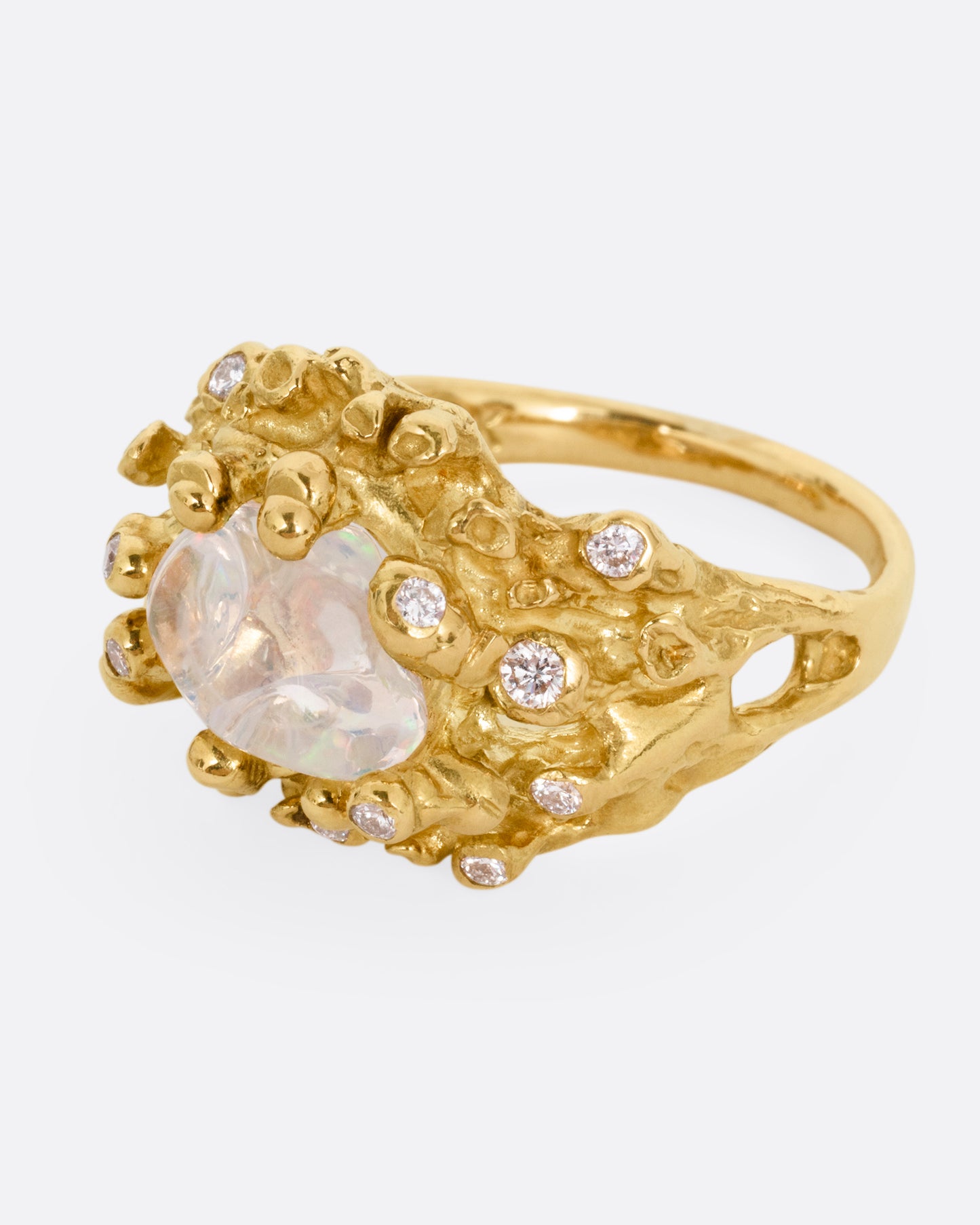 A yellow gold ring with a dimensional nest-like setting studded with diamonds and an opal, shown from the side.