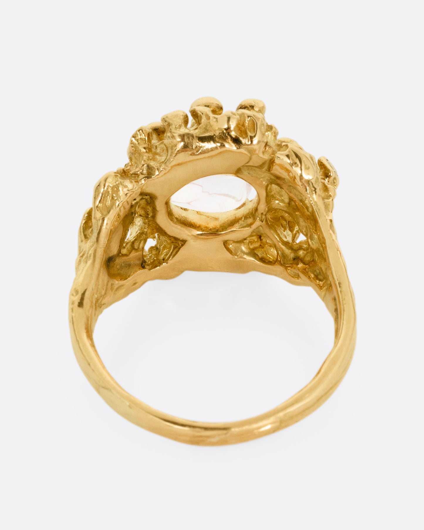 A yellow gold ring with a dimensional nest-like setting studded with diamonds and an opal, shown from the back.