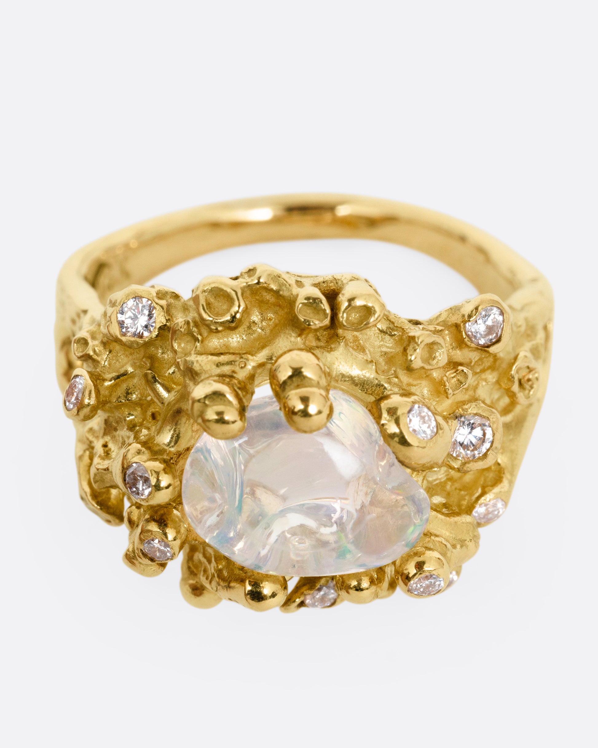 A yellow gold ring with a dimensional nest-like setting studded with diamonds and an opal, shown from the front.