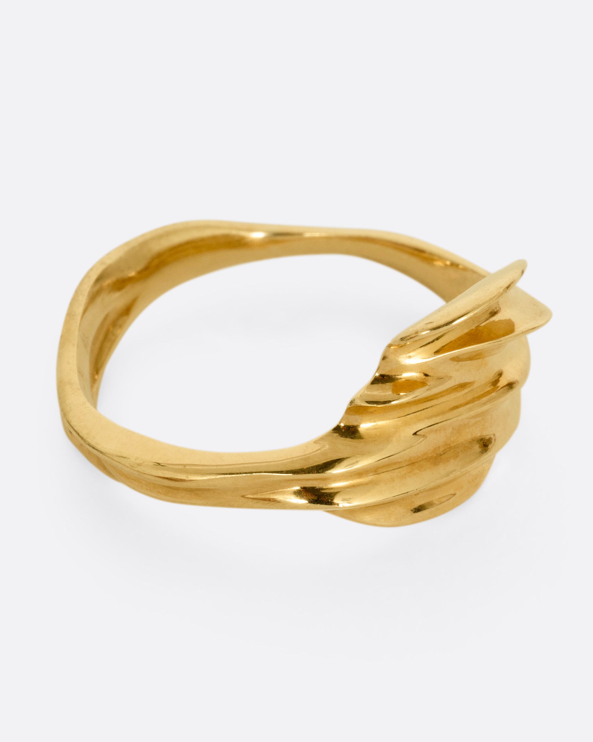 A yellow gold ring with a fluid, dimensional silhouette and narrow back, shown from the side.