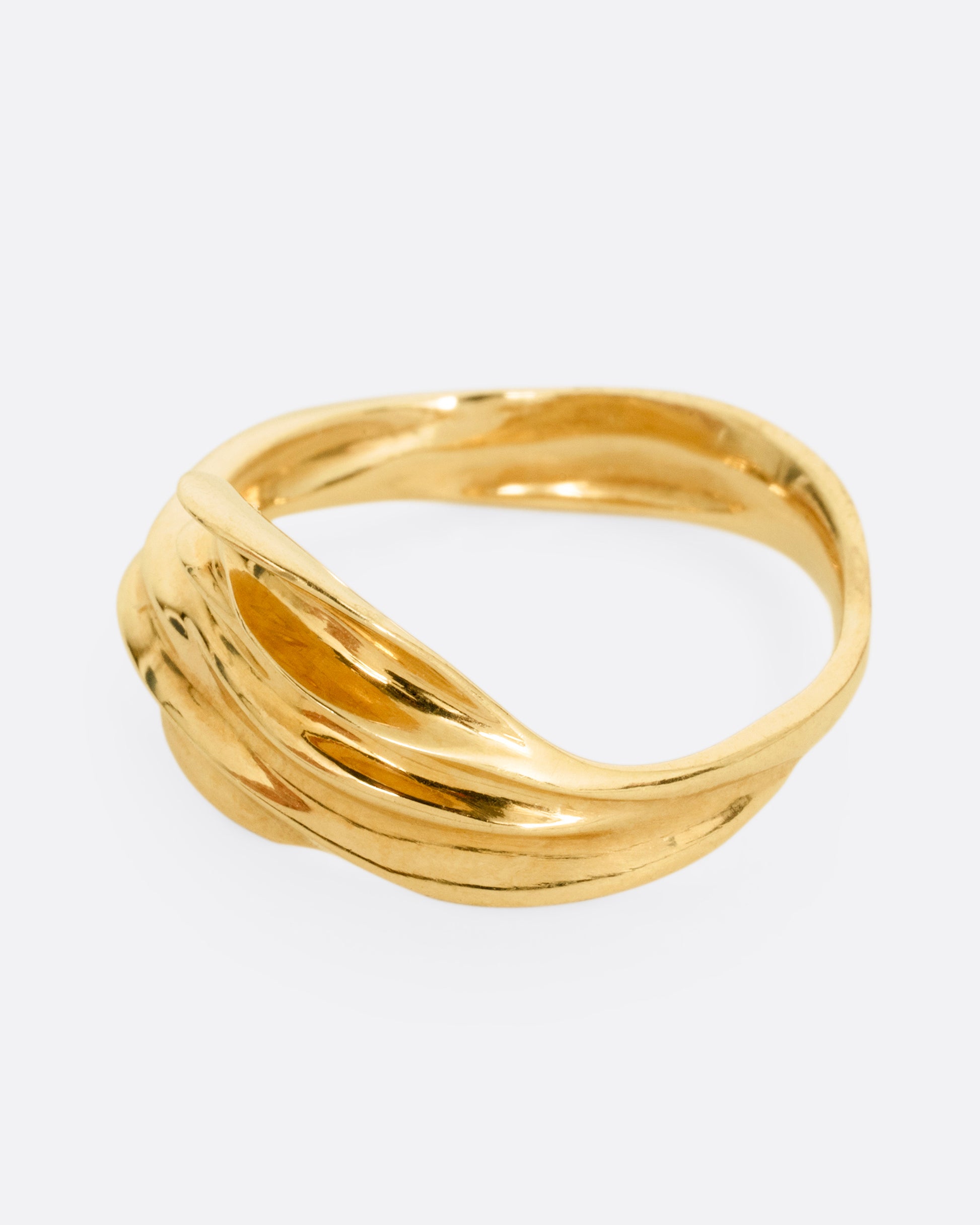A yellow gold ring with a fluid, dimensional silhouette and narrow back, shown from the side.