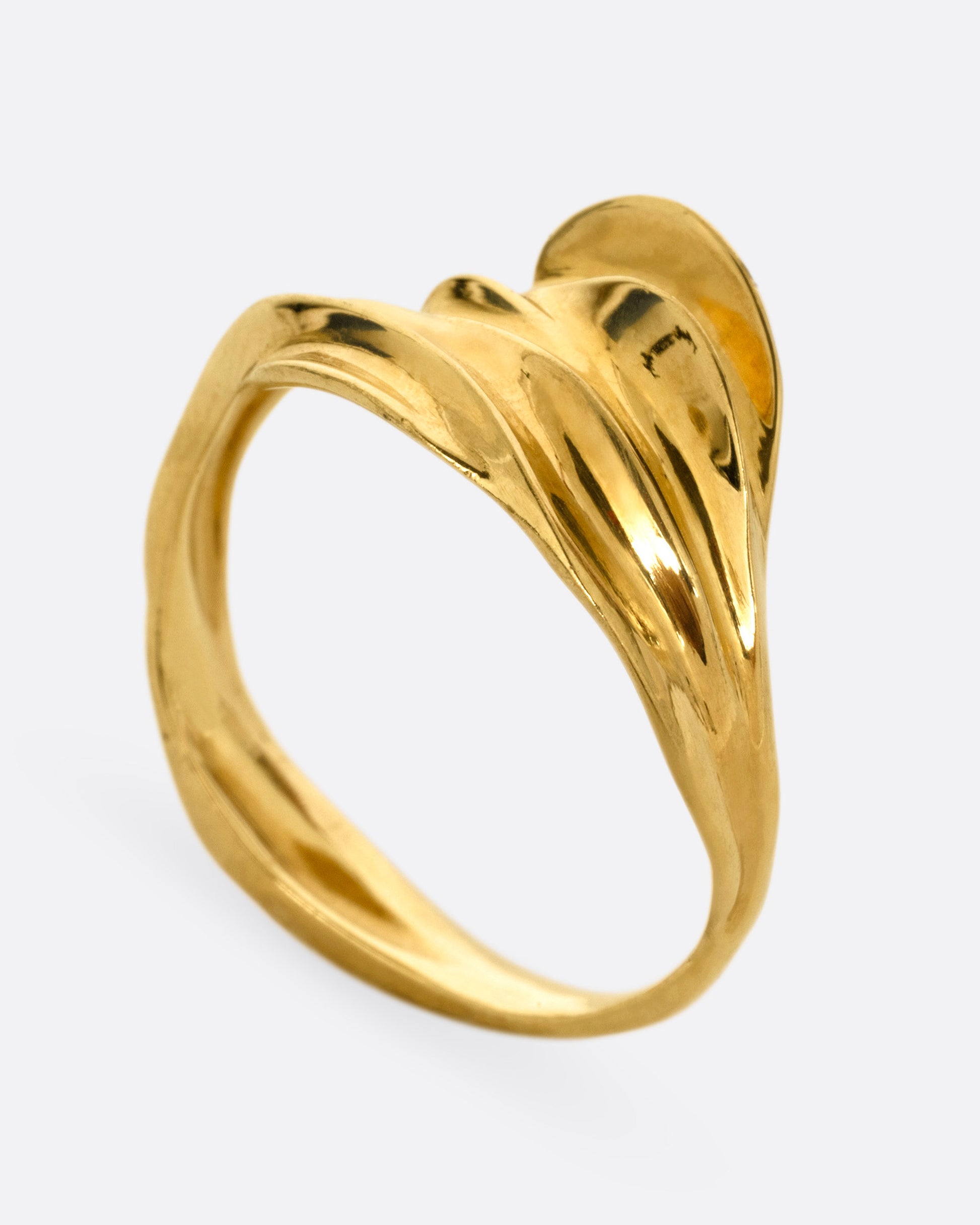A yellow gold ring with a fluid, dimensional silhouette and narrow back, shown from the side standing up.