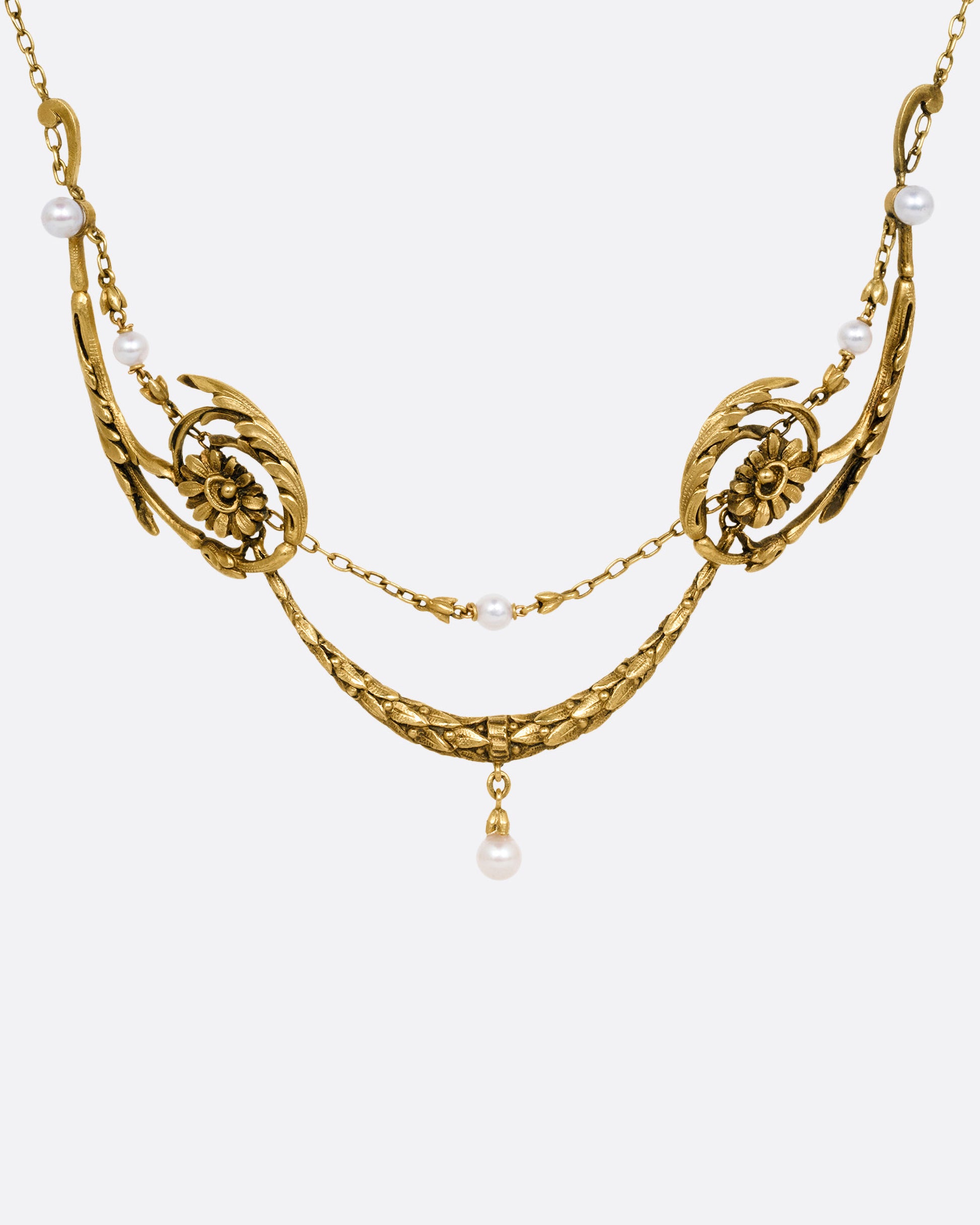 A yellow gold necklace with pearls and flower details, shown from the front.