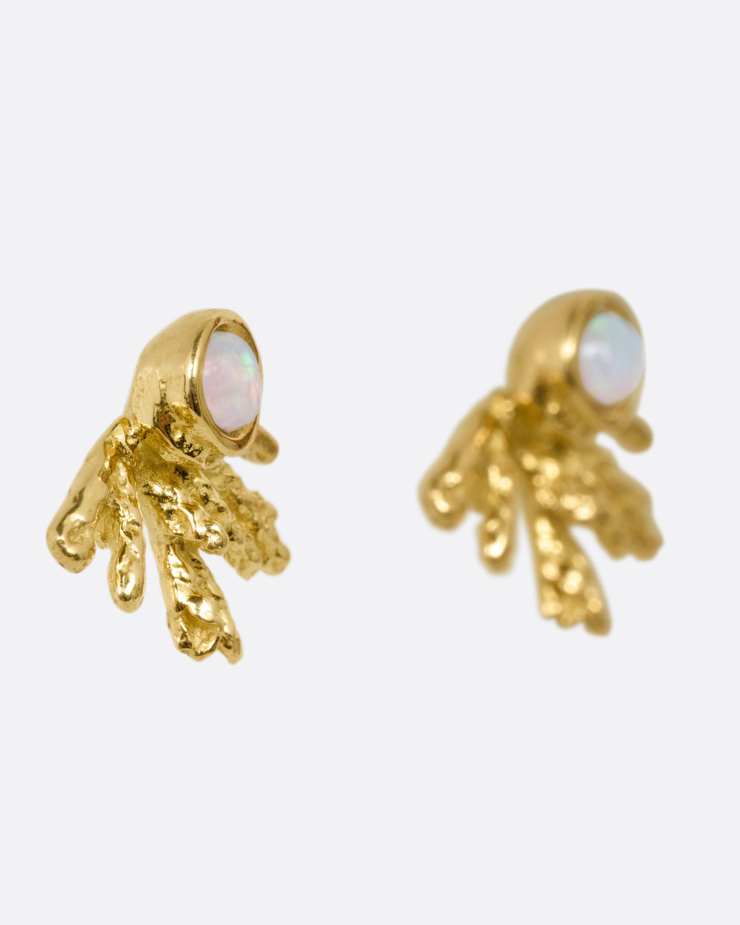 A pair of yellow gold stud earrings with tentacle-like tails and opals, shown from the side.