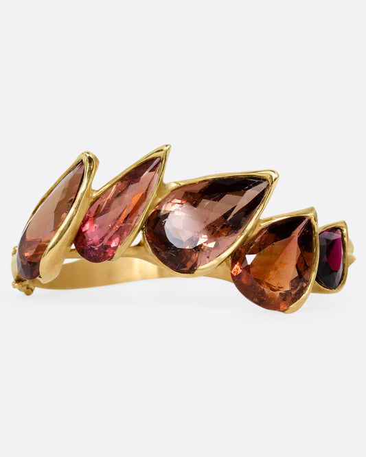 A yellow gold bracelet with five teardrop shaped tourmalines, shown from the front.