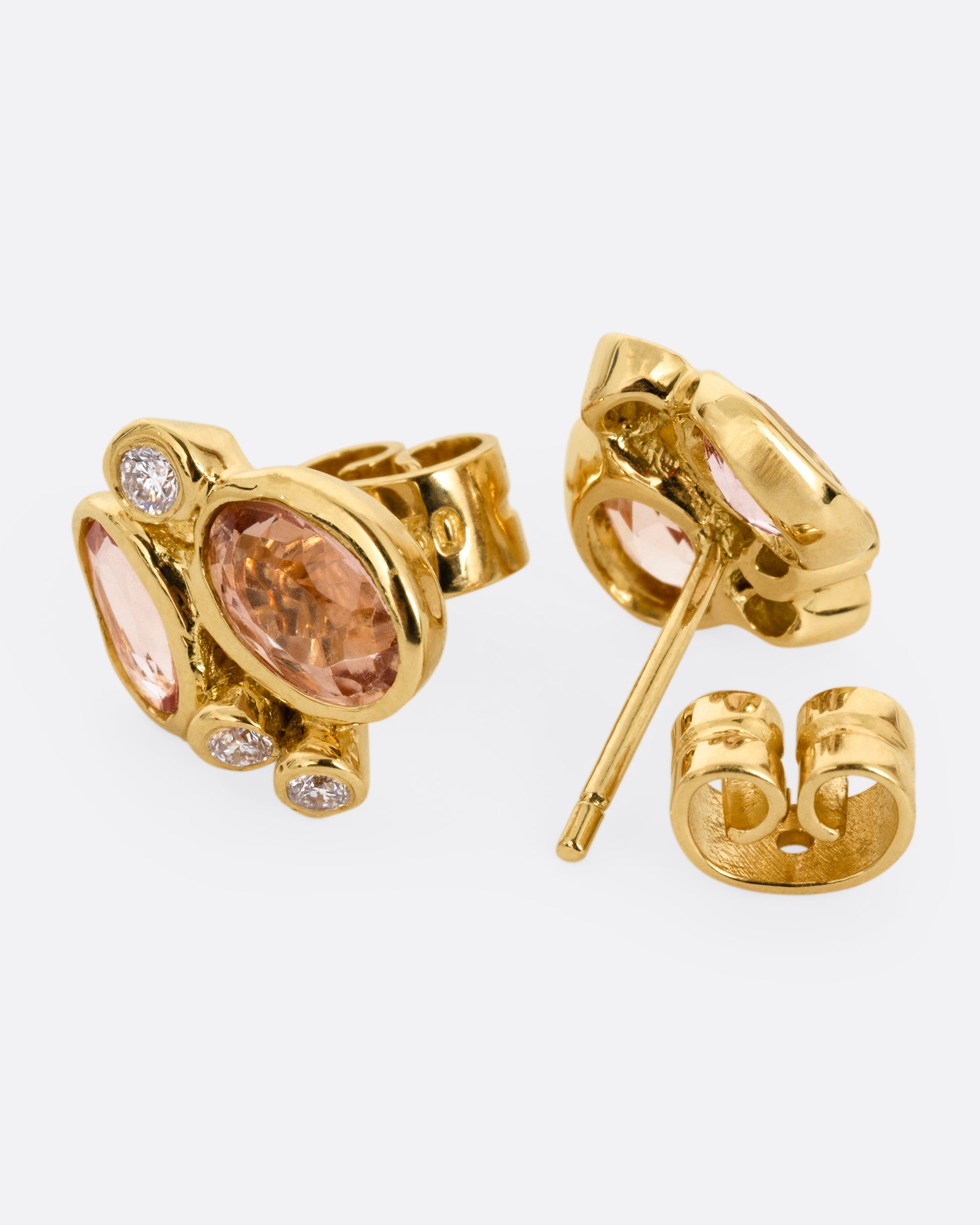 A pair of yellow gold stud earrings with clusters of pink tourmalines and white diamonds. One earring is shown from the front, the other from the back open.