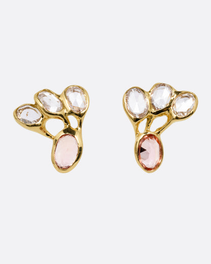 A pair of yellow gold stud earrings with freeform rose cut diamonds and pink tourmalines, shown from the front.