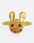A yellow gold ring with a bear face with tourmaline and ruby eyes and mouth, shown from the front.