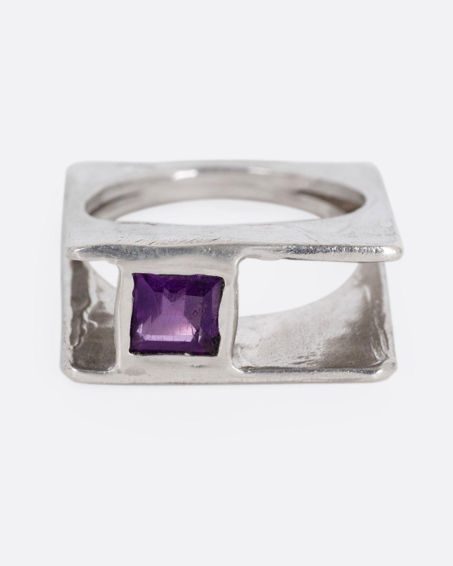 A silver square ring that widens to reveal a princess cut amethyst, shown from the front.