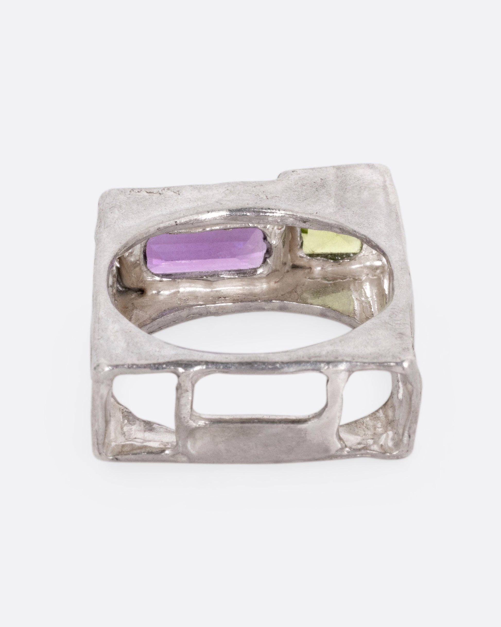 A silver square ring with a princess cut peridot and baguette amethyst, shown from the back.