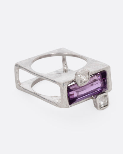 A silver square ring with an amethyst baguette and two square topaz, shown from the side.
