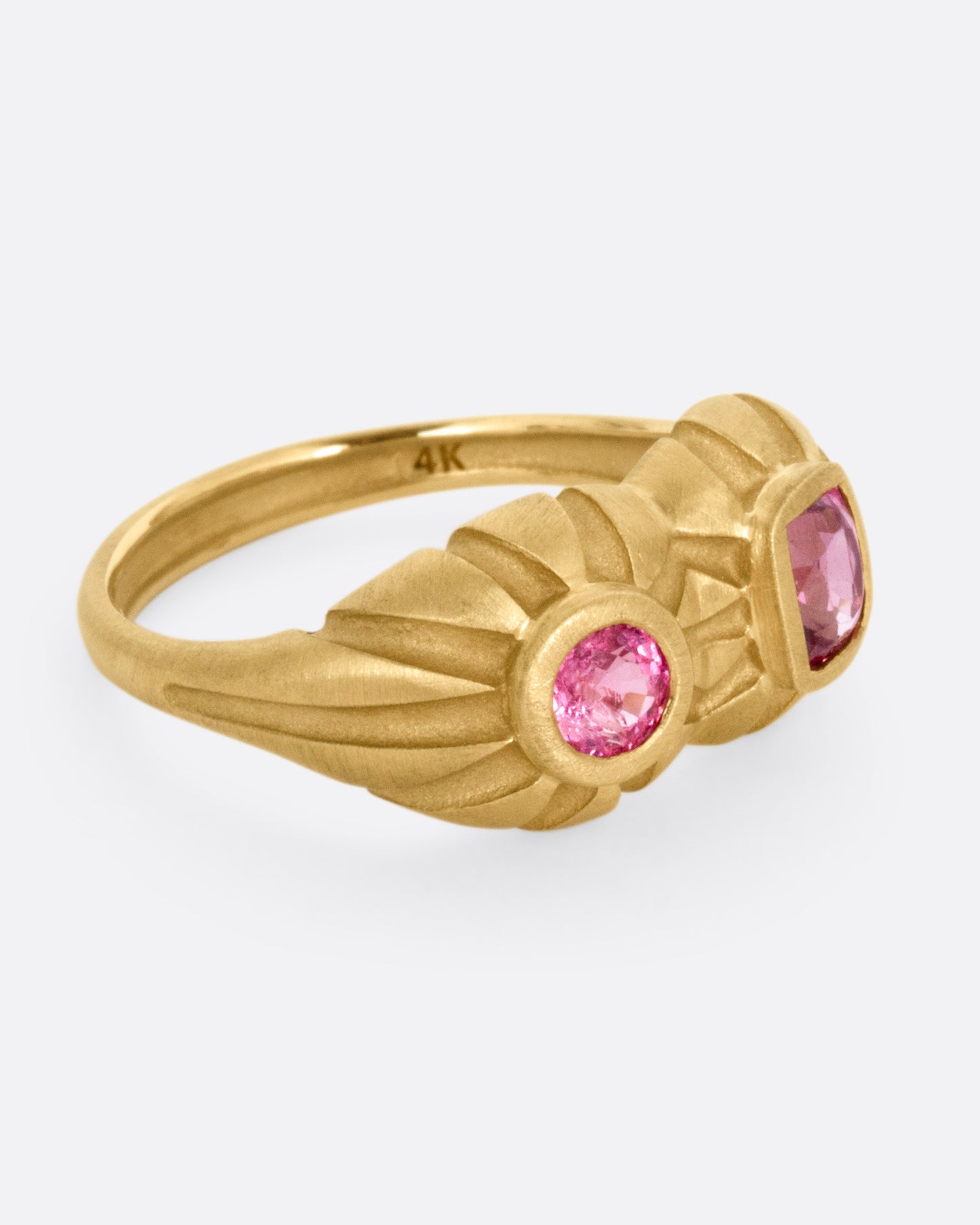 A yellow gold dimensional domed ring with two pink spinels, one round and one cushion cut, shown from the side.