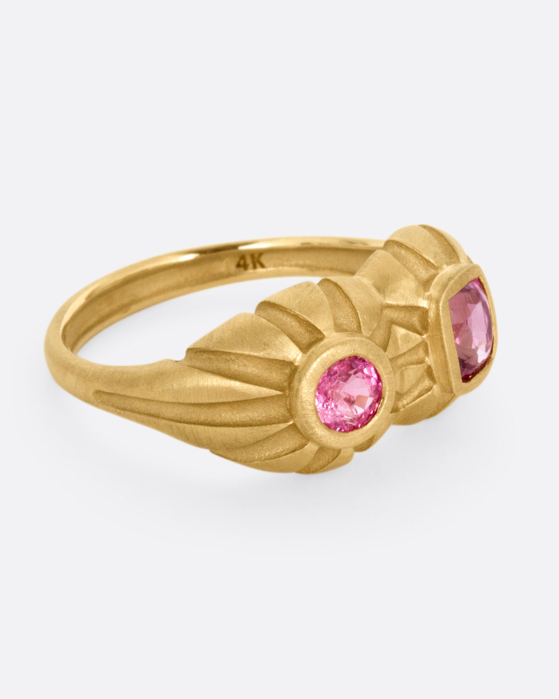 A yellow gold dimensional domed ring with two pink spinels, one round and one cushion cut, shown from the side.