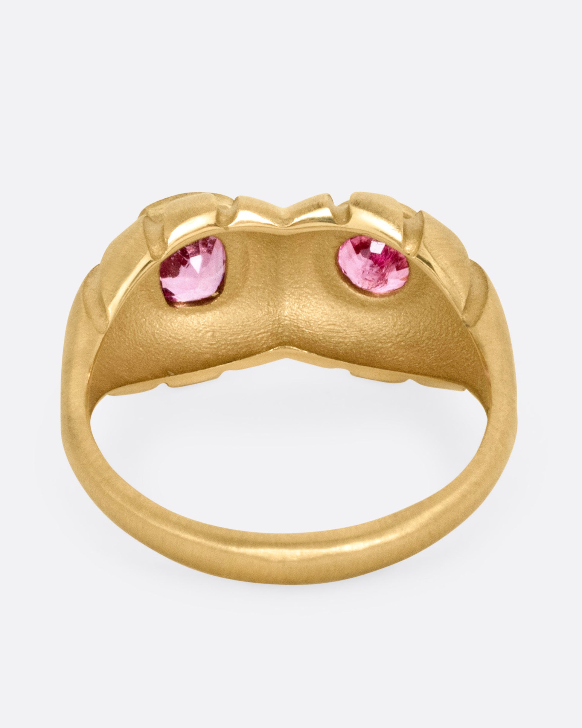 A yellow gold dimensional domed ring with two pink spinels, one round and one cushion cut, shown from the back.