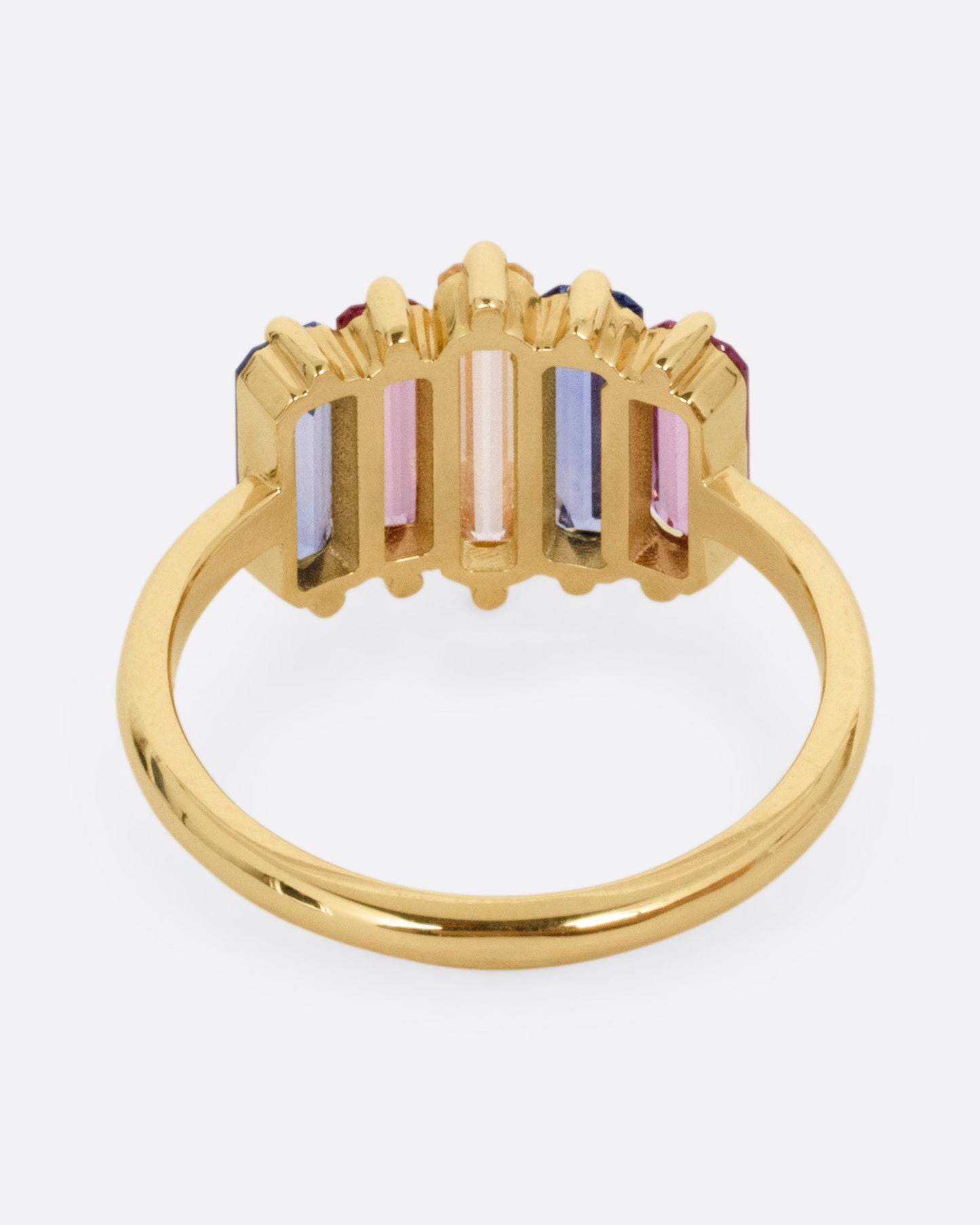A yellow gold queue of pastel colored sapphire baguettes, shown from the back.