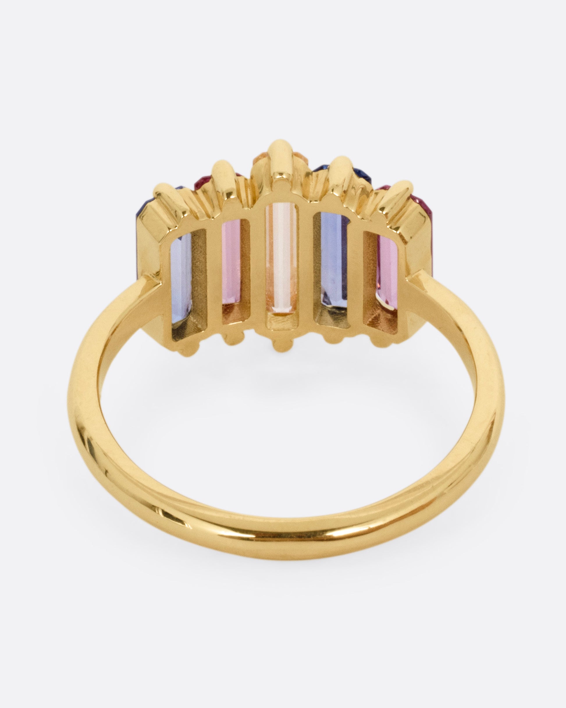 A yellow gold queue of pastel colored sapphire baguettes, shown from the back.
