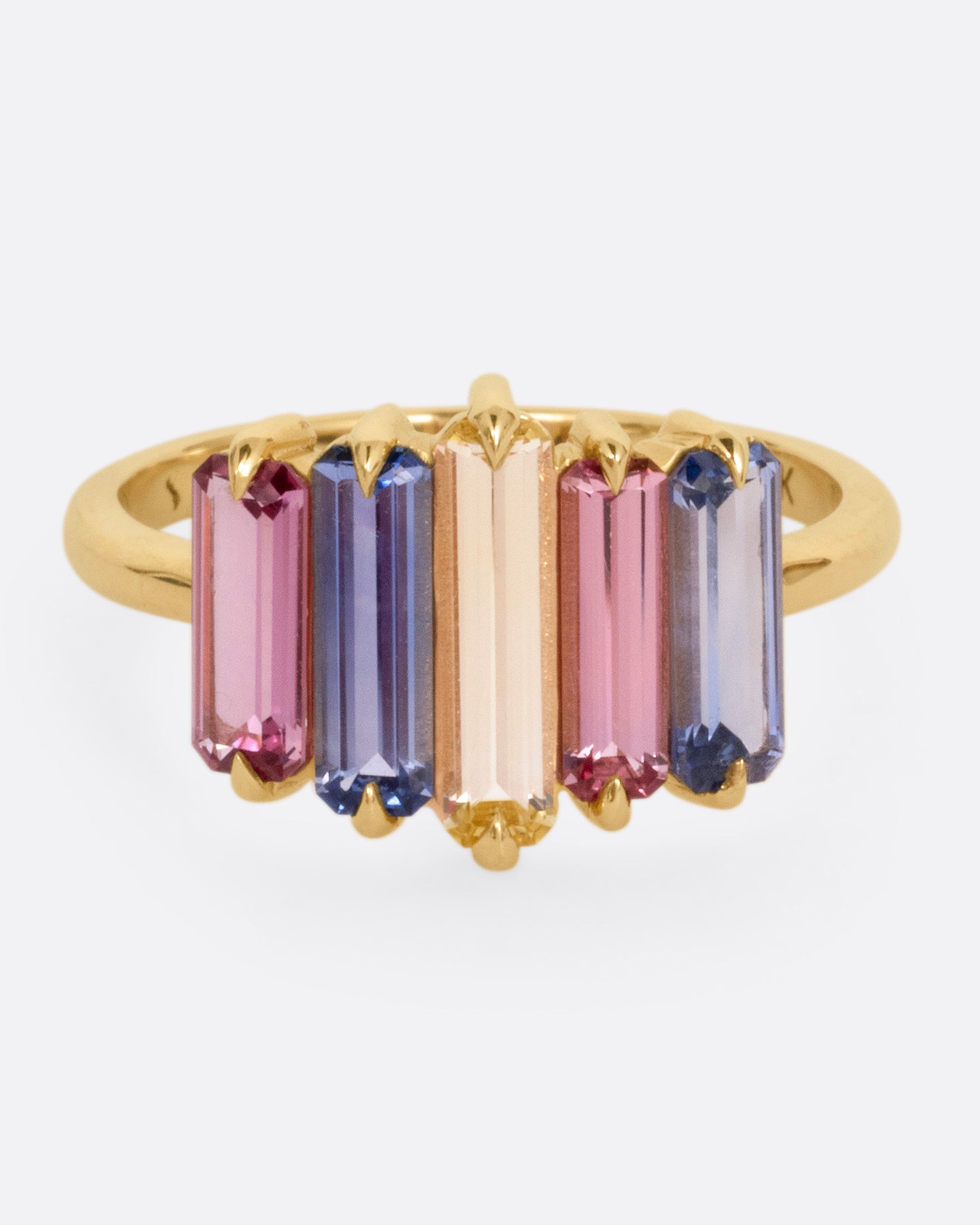 A yellow gold queue of pastel colored sapphire baguettes, shown from the front.
