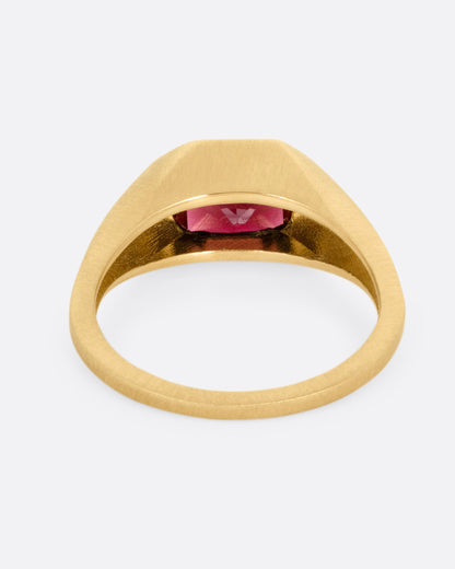 A yellow gold signet ring with a garnet, shown from the back.