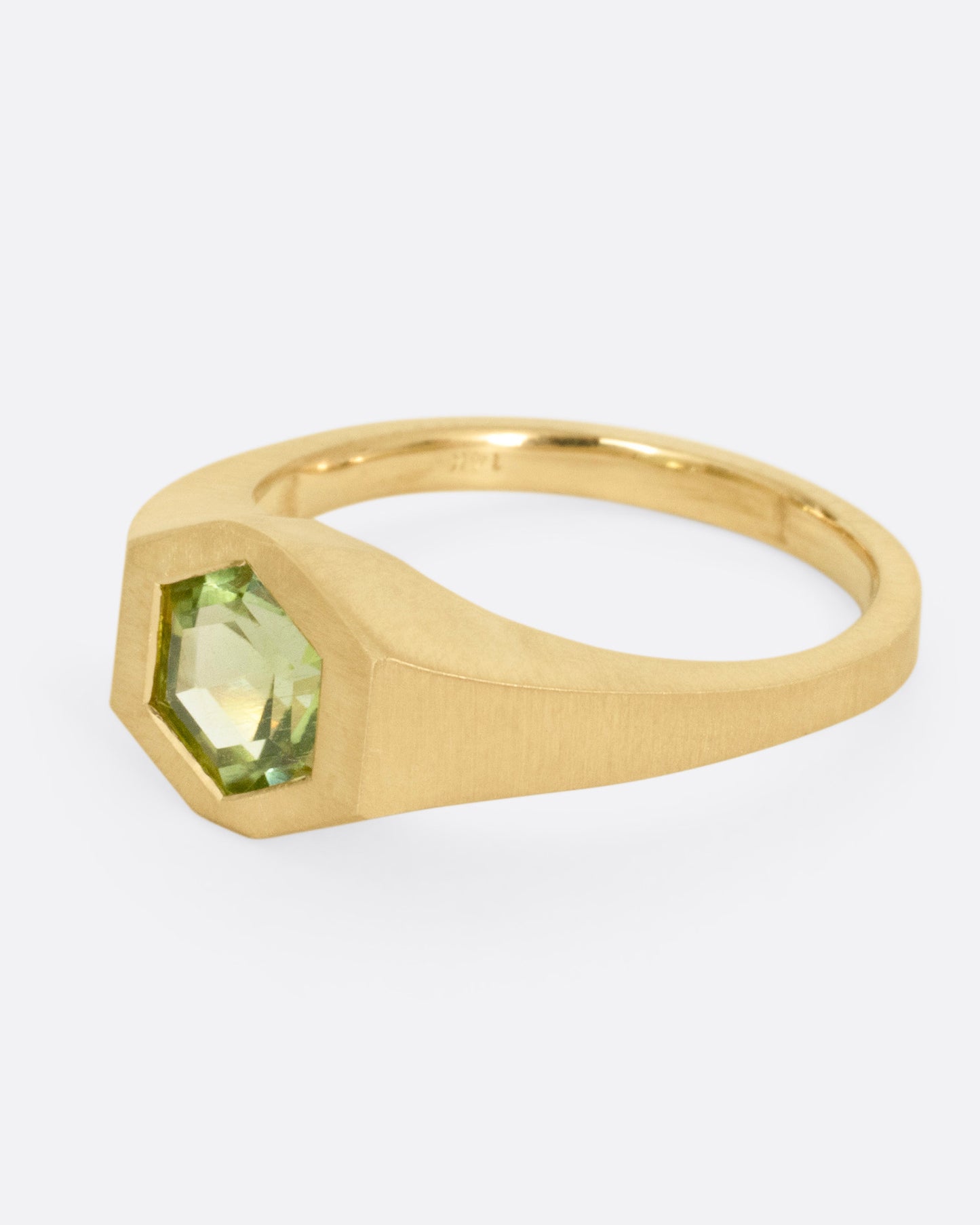A yellow gold ring with a green hexagonal tourmaline, shown from the side.
