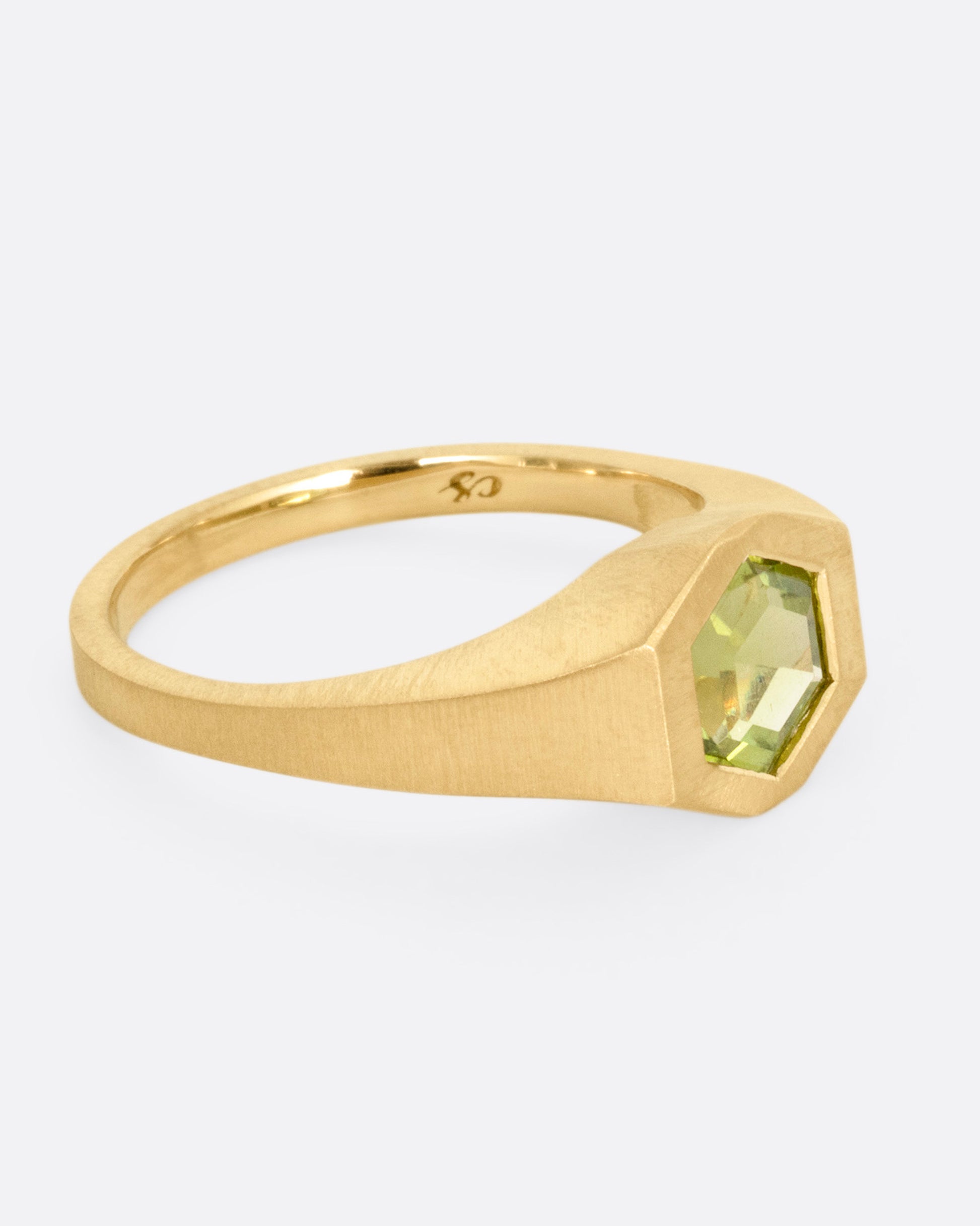 A yellow gold ring with a green hexagonal tourmaline, shown from the side.