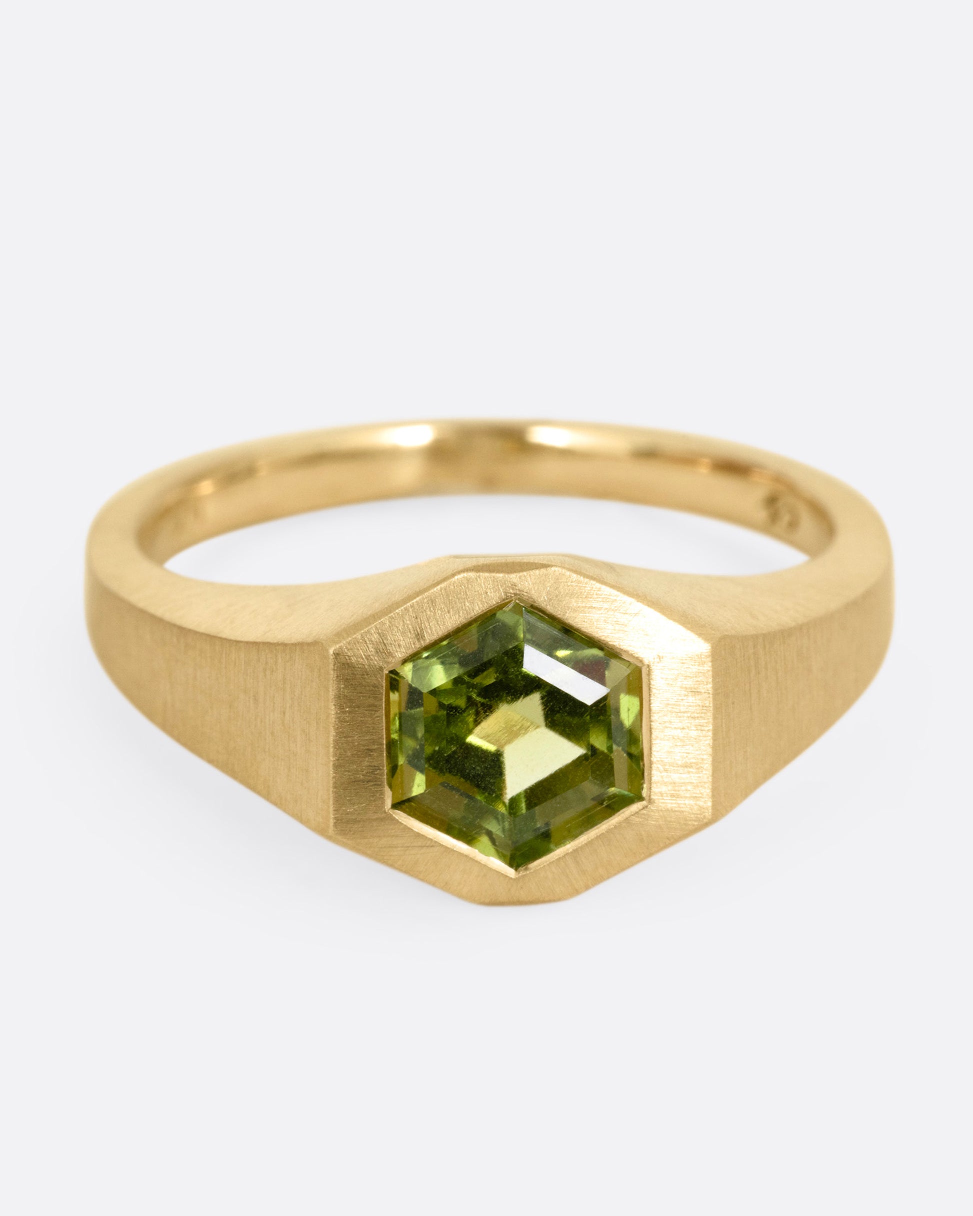 A yellow gold ring with a green hexagonal tourmaline, shown from the front.