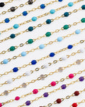 A photo of numerous yellow gold chains with different colors of resin beads.