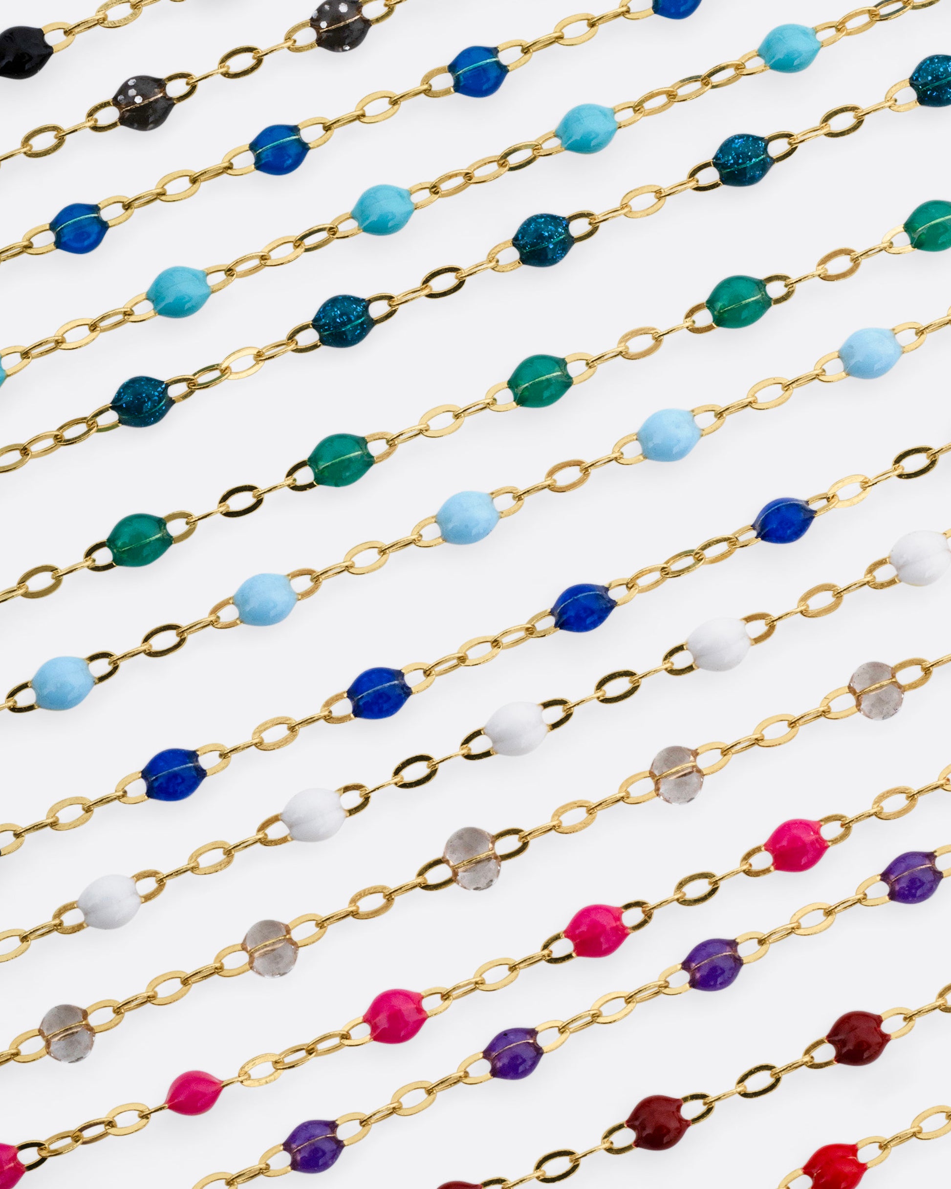 A photo of numerous yellow gold chains with different colors of resin beads.