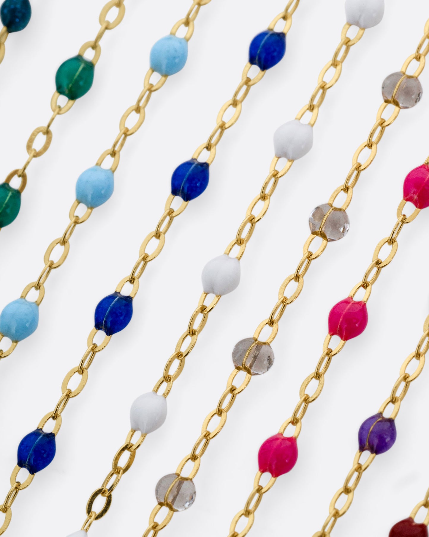 A photo of numerous yellow gold chains with different colors of resin beads.