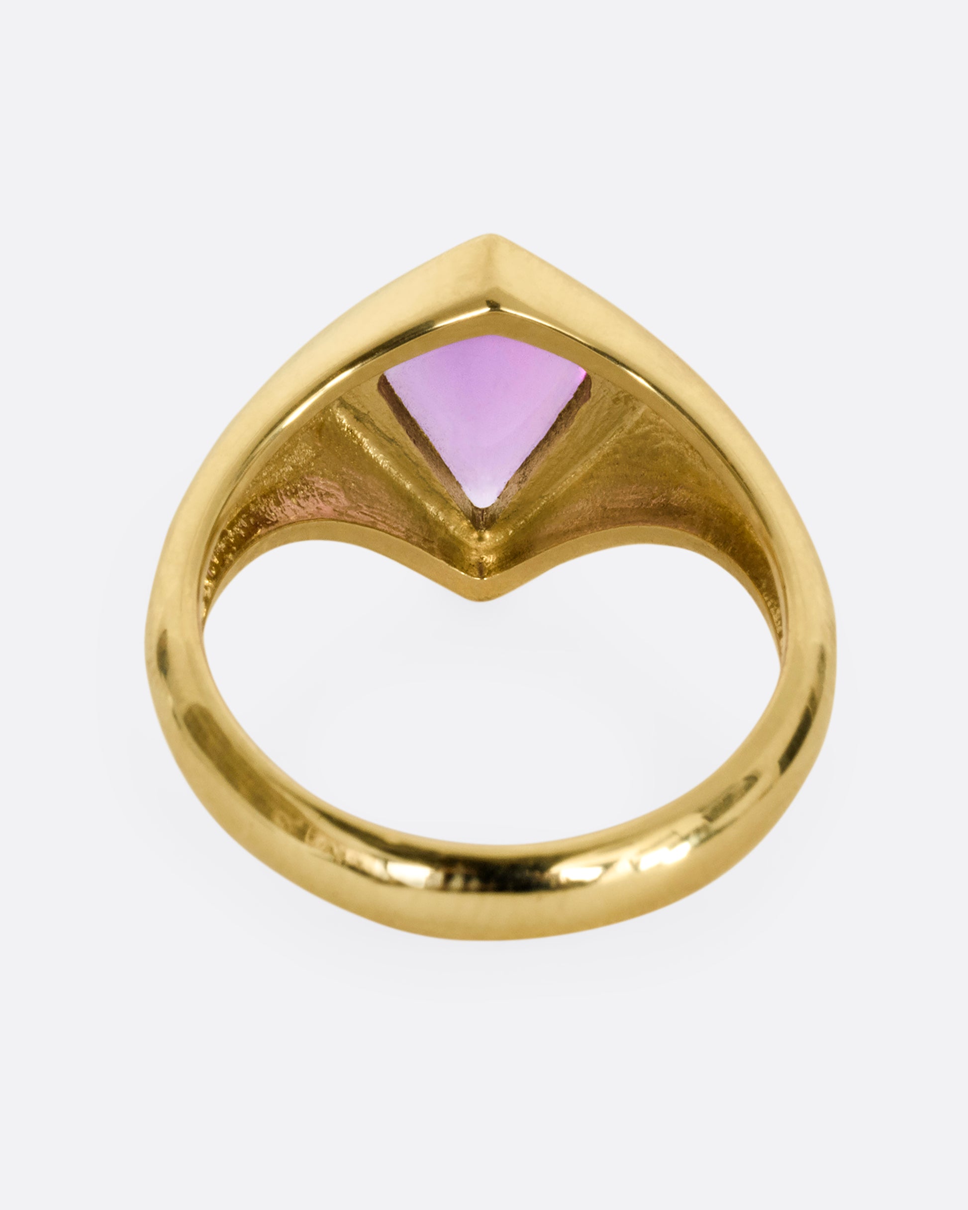 A yellow gold ring with a cabochon maroon kite shaped sapphire. Shown from the back.