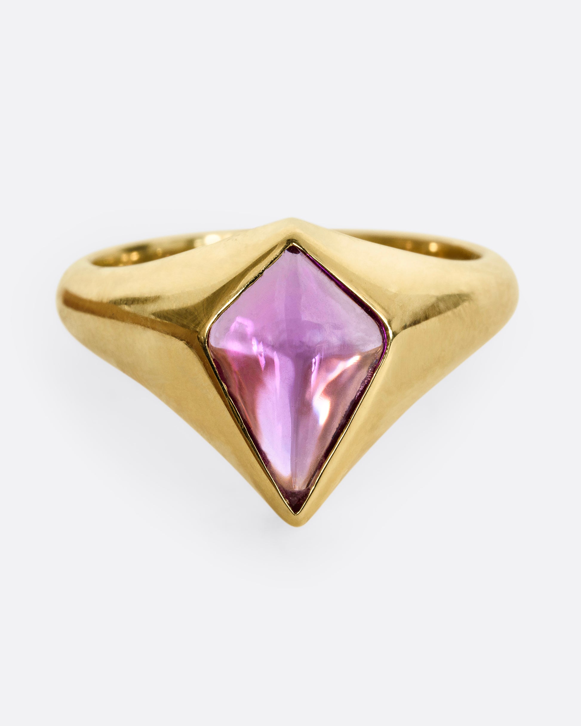 A yellow gold ring with a cabochon maroon kite shaped sapphire. Shown from the front.